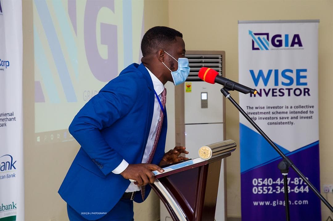 A speaker at a lectern presenting the Wise Investor plan